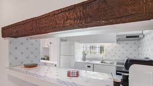 Una cocina con encimera blanca, una cafetera y una ventana con vistas al exterior.