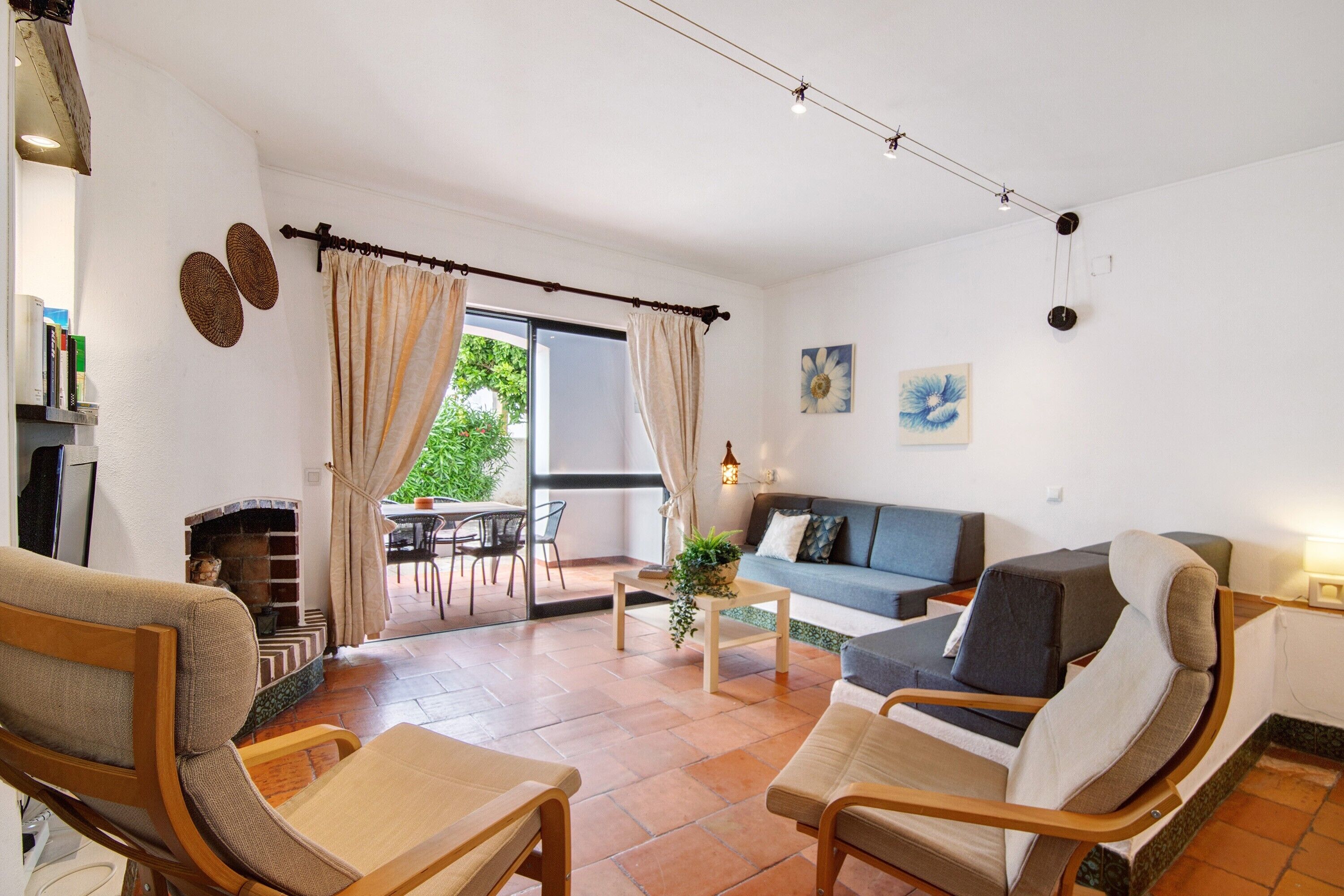 A living room with a sofa, two armchairs, a coffee table, a fireplace, and a dining area with a table and chairs.