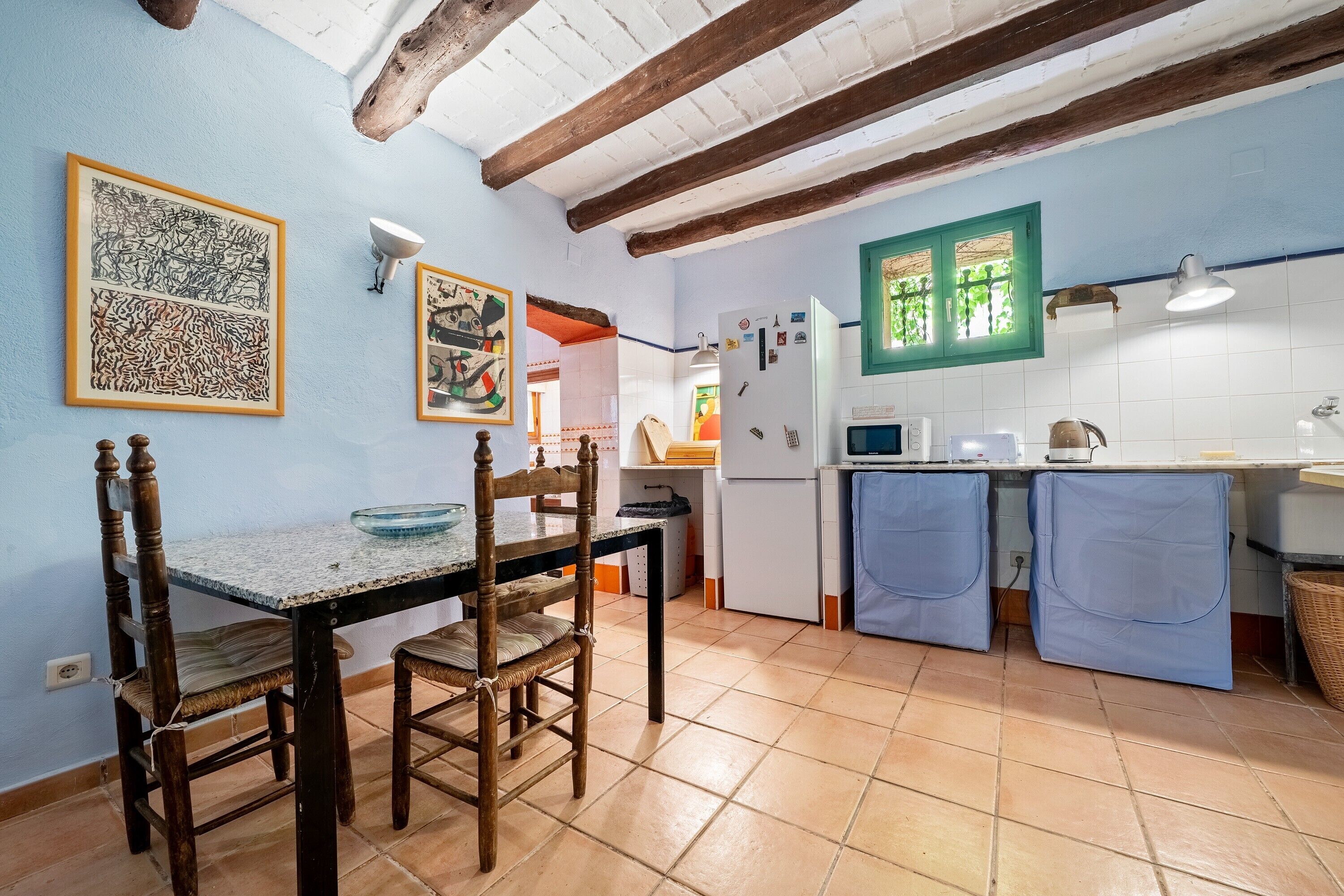 A kitchen with a dining table, chairs, a refrigerator, and a microwave.