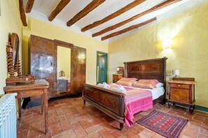A bedroom with a wooden bed, a mirror, a dresser, and a radiator.