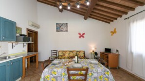 A kitchen with a dining table set for four, a wooden ceiling, and a wall-mounted air conditioner. - Farmhouse "Il Pino - Mandorlo" with Shared Pool, Private Terrace & Wi-Fi (Cecina)