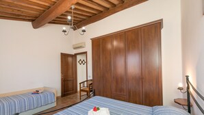 A bedroom with two beds, wooden wardrobe, and a chair. - Farmhouse "Il Pino - Tiglio" with Shared Pool, Private Terrace & Wi-Fi (Cecina)