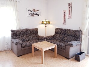 A living room with two patterned sofas, a wooden coffee table, a floor lamp, and artwork on the walls.