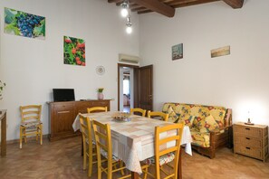 Ein Essbereich mit Tisch, Stühlen, einer Couch und einem Fernseher.
