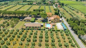 Luchtbeeld van een landelijk gelegen bezit met een groot huis, een zwembad en wijngaarden.