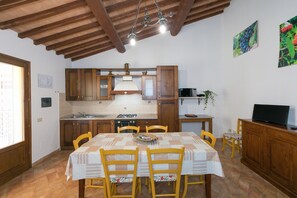 Une cuisine avec des meubles en bois, un pare-feu en carrelage, une cuisinière et un coin repas comprenant une table et des chaises.