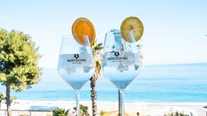 Deux verres d’eau, chacun agrémenté d’une tranche d’orange et d’une tranche de citron, sont posés sur une table d’où l’on a vue sur l’océan et la plage.