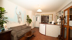 Un espace d’accueil comprenant un canapé, une table basse, un comptoir de réception, une horloge murale et une plante décorative.