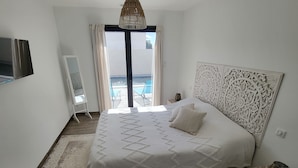 A bedroom with a large bed, a view of the pool, and a white headboard. - La Zenitude, a beautiful single-storey property with well-appointed features (Sérignan)