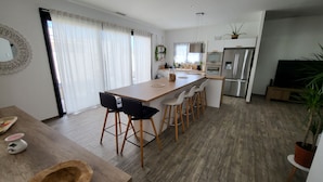 A modern kitchen with a central island, bar stools, and stainless steel appliances. - La Zenitude, a beautiful single-storey property with well-appointed features (Sérignan)