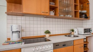 Eine kompakte Küche mit Einbauofen, Mikrowelle, Kaffeemaschine und Spüle.