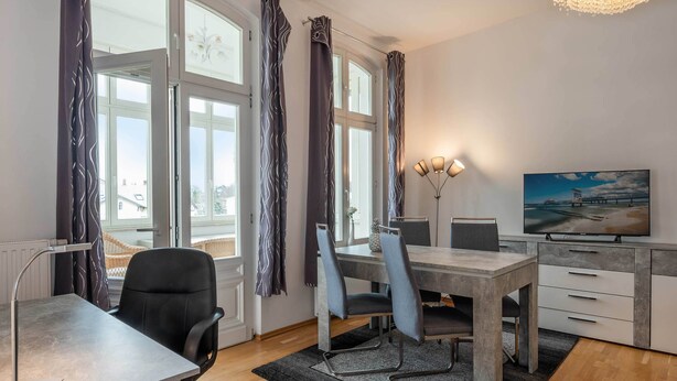 Ein modernes Wohnzimmer mit Essbereich, Fernseher und Blick ins Freie.
