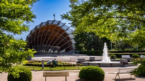 Un parc amb un edifici gran i circular, una font i bancs.