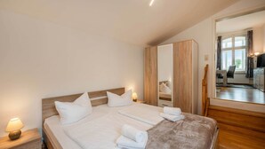A hotel room with a large bed, a wardrobe, a mirror, and a view of the outside.