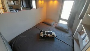 Un dormitorio pequeño con cama, almohadas, armario y ventana.