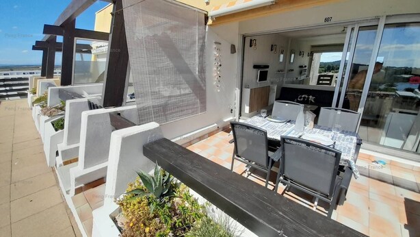 Un patio al aire libre con una mesa y sillas para comer, rodeado de macetas con diversas plantas.