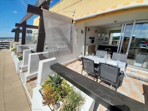 Ein möblierter Patio-Bereich mit Esstisch und Stühlen, umgeben von Pflanzgefäßen mit verschiedenen Pflanzen.