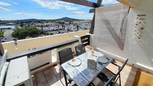 Un balcón con una mesa lista para comer, una pizarra y vistas a un pueblo y colinas.