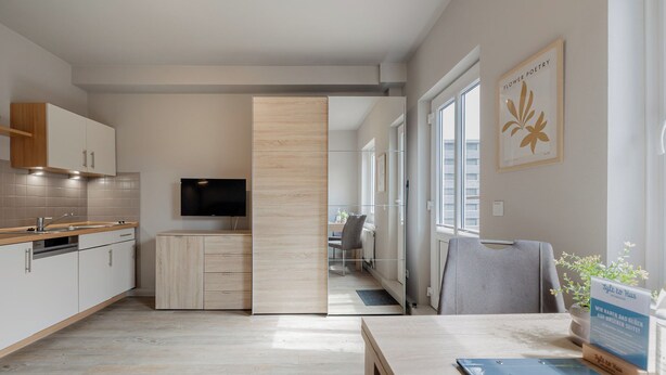 Una cocina moderna con armarios de madera, un televisor integrado y un comedor con mesa y sillas.