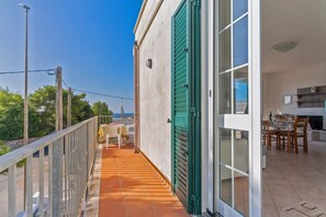 Un balcone con tavolo e sedie, vista sul mare e zona pranzo con TV e camino.