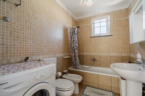 Un bagno con lavatrice, wc, vasca e lavandino.