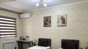 A hotel room with two single beds, a desk, a chair, and a radiator. - Yantai Hotel (Tashkent)