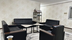 A room with a sectional sofa, two armchairs, a coffee table, and a decorative vase. - Yantai Hotel (Tashkent)