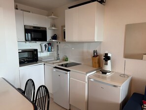 A compact kitchen with white cabinetry, a microwave, a coffee machine, and a dishwasher.