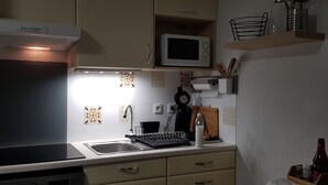 Una cocina equipada con microondas, lavamanos y hervidor.