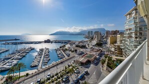 A marina with boats, a road with cars, and buildings with balconies.