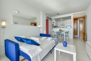 A modern hotel room with a bed, a small table, and a kitchenette in the background. - NAUTICO, Apartment for rent in Calpe for 4 pax with swimming pool and private parking (Calpe)