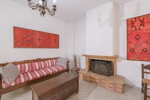 A living room with a sofa, a fireplace, and two large patterned wall hangings.