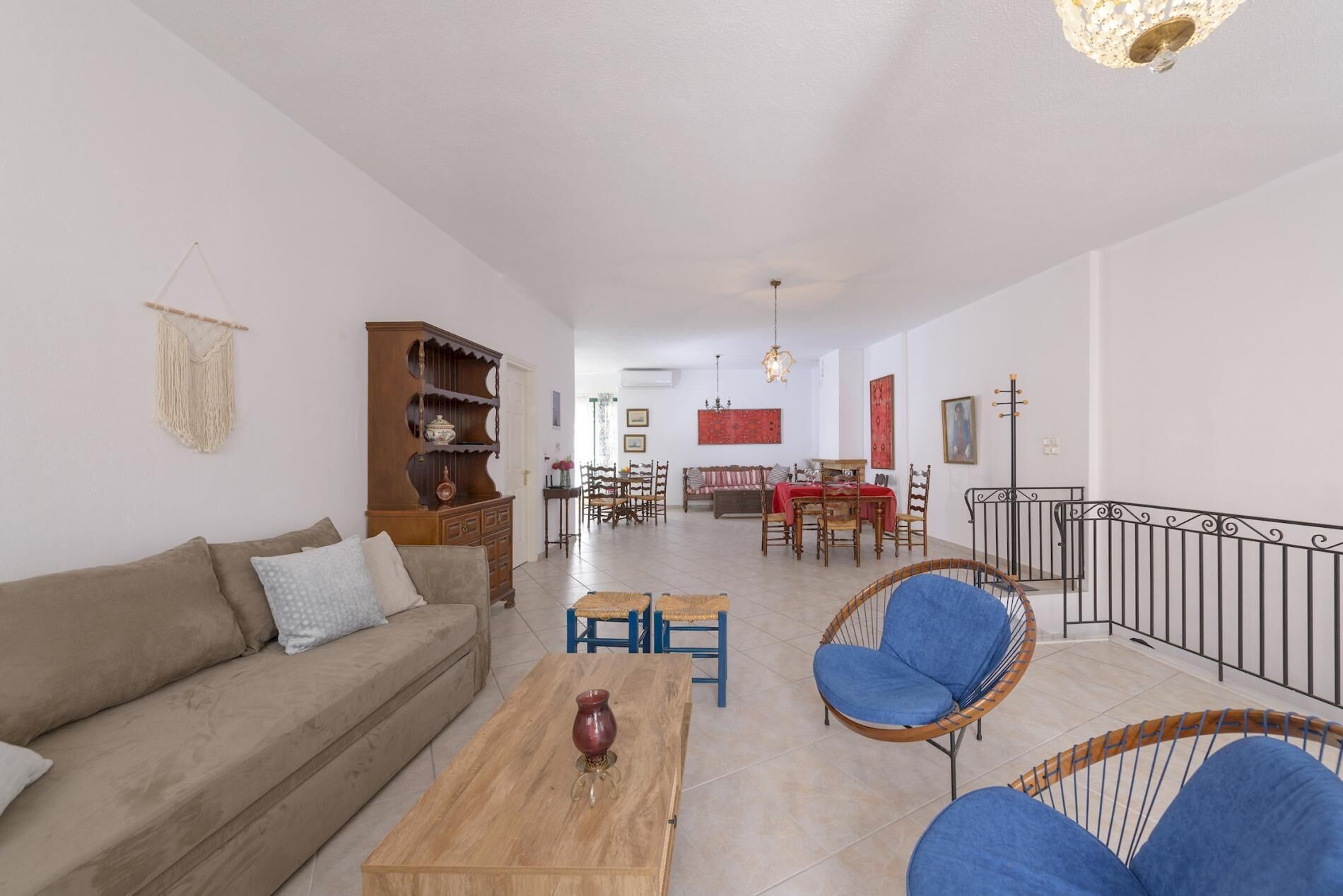 Ein Wohnzimmer mit Sofa, Couchtisch und Stühlen, ein Essbereich mit Tisch und Stühlen sowie eine Treppe mit Geländer.