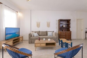 A living room with a sofa, coffee table, TV, and two blue chairs.