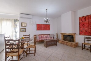 Una sala de estar con chimenea, una mesa de comedor con sillas, un sofá y una araña.