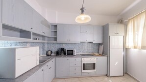 A modern kitchen with grey cabinets, a Bosch dishwasher, a microwave, a coffee maker, and a refrigerator. - Rethymno Heart (Rethymno)