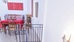 A staircase with a handrail, a dining area with a red tablecloth, and a wall with a decorative light fixture. - Rethymno Heart (Rethymno)