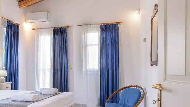 A bedroom with a wooden ceiling, a bed, a chair, and curtains. - Rethymno Heart (Rethymno)