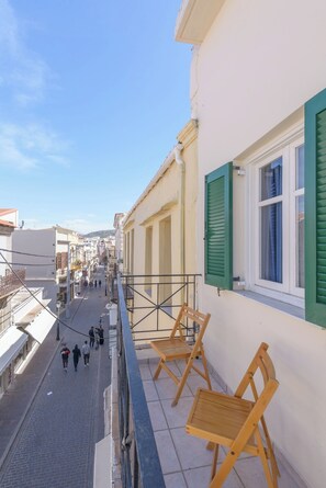 A narrow street with buildings on either side, a balcony with wooden chairs, and a clear blue sky. - Rethymno Heart (Rethymno)