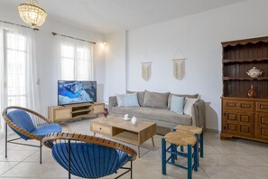 A living room with a television, sofa, chairs, a coffee table, and a wooden cabinet.