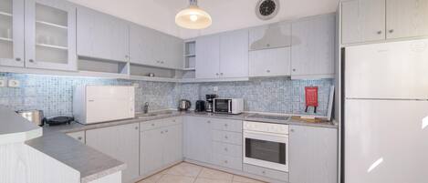 A modern kitchen with light wood cabinetry, a Bosch microwave, a coffee maker, and a refrigerator.
