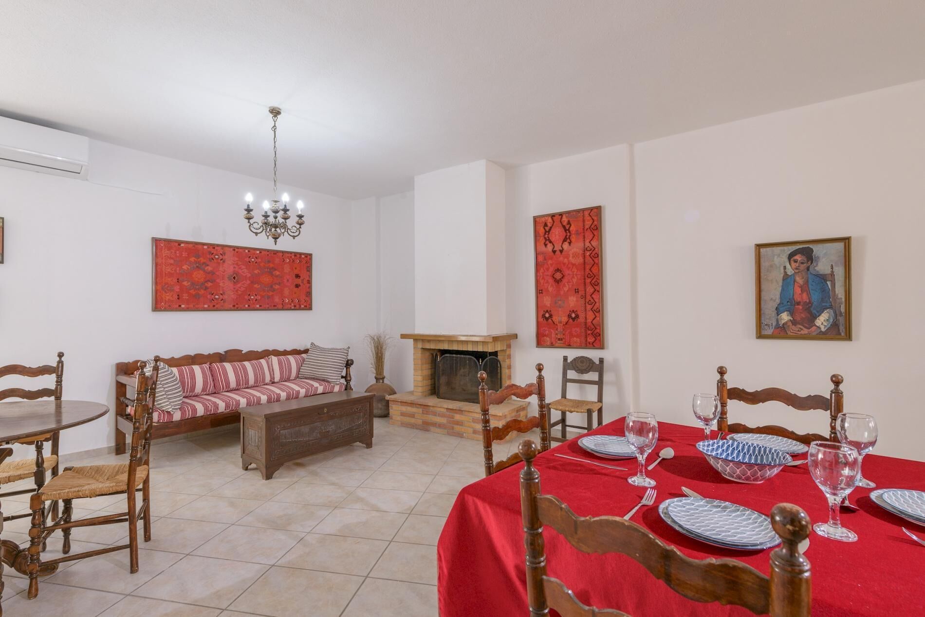 A dining area with a red tablecloth, wooden chairs, and a fireplace.