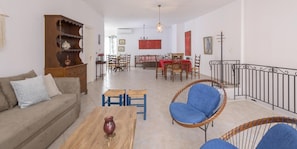 Ein Wohnzimmer mit Sofa, Couchtisch und Sesseln, ein Essbereich mit Tisch und Stühlen sowie eine Treppe mit Geländer.