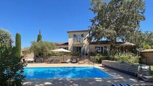 A swimming pool with lounge chairs and a building with a balcony. - Villa de Charme, à Proximité Immédiate D'uzes et du Pont du Gard (Argilliers)