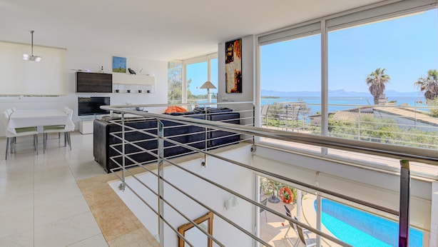 Ein modernes Wohnzimmer mit großem Fenster, Essbereich und Blick auf Pool und Berge.