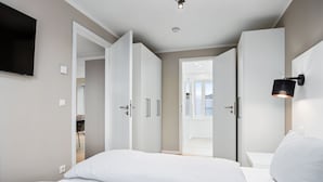 Ein modernes Hotelzimmer mit Bett, weißen Wänden und einem an der Wand befestigten Flachbildfernseher.
