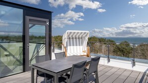 Ein Balkon mit Tisch und Stühlen, eine Glastür und Meerblick.