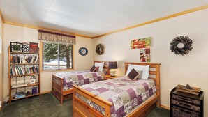 Une chambre confortable avec deux lits en bois, une bibliothèque et une fenêtre donnant sur les arbres.