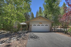 A single-story building with a garage, surrounded by trees and a gravel driveway.