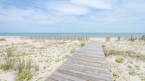 A wooden boardwalk leading to a sandy beach with a wooden fence in the background. - Beachfront, Pool, Spa, Pet Friendly, Elevator, Decks, fire pit, Games! (Saint George Island)